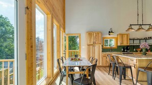 Een moderne keuken met houten kastjes, een groot eiland en een eetgedeelte met tafel en stoelen.