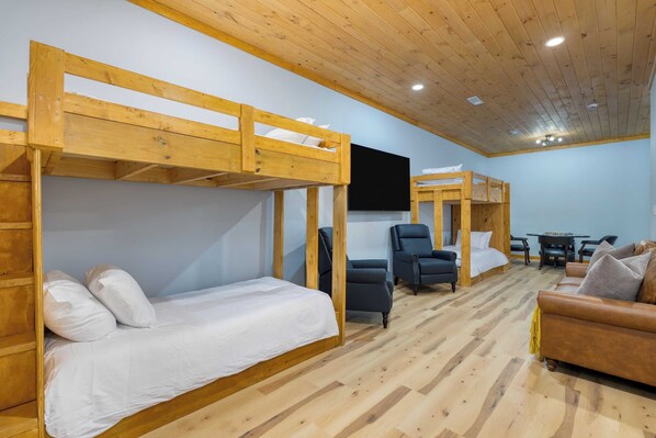 A room with bunk beds, a sofa, a chair, and a table. - Cabin w/ Hot Tub, Game Room & Scenic Smoky Mountain Views Perfect by Avantstay (Gatlinburg)