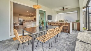 Una cocina moderna con comedor, que incluye una mesa grande y sillas, un ventilador de techo y vistas del salón contiguo.