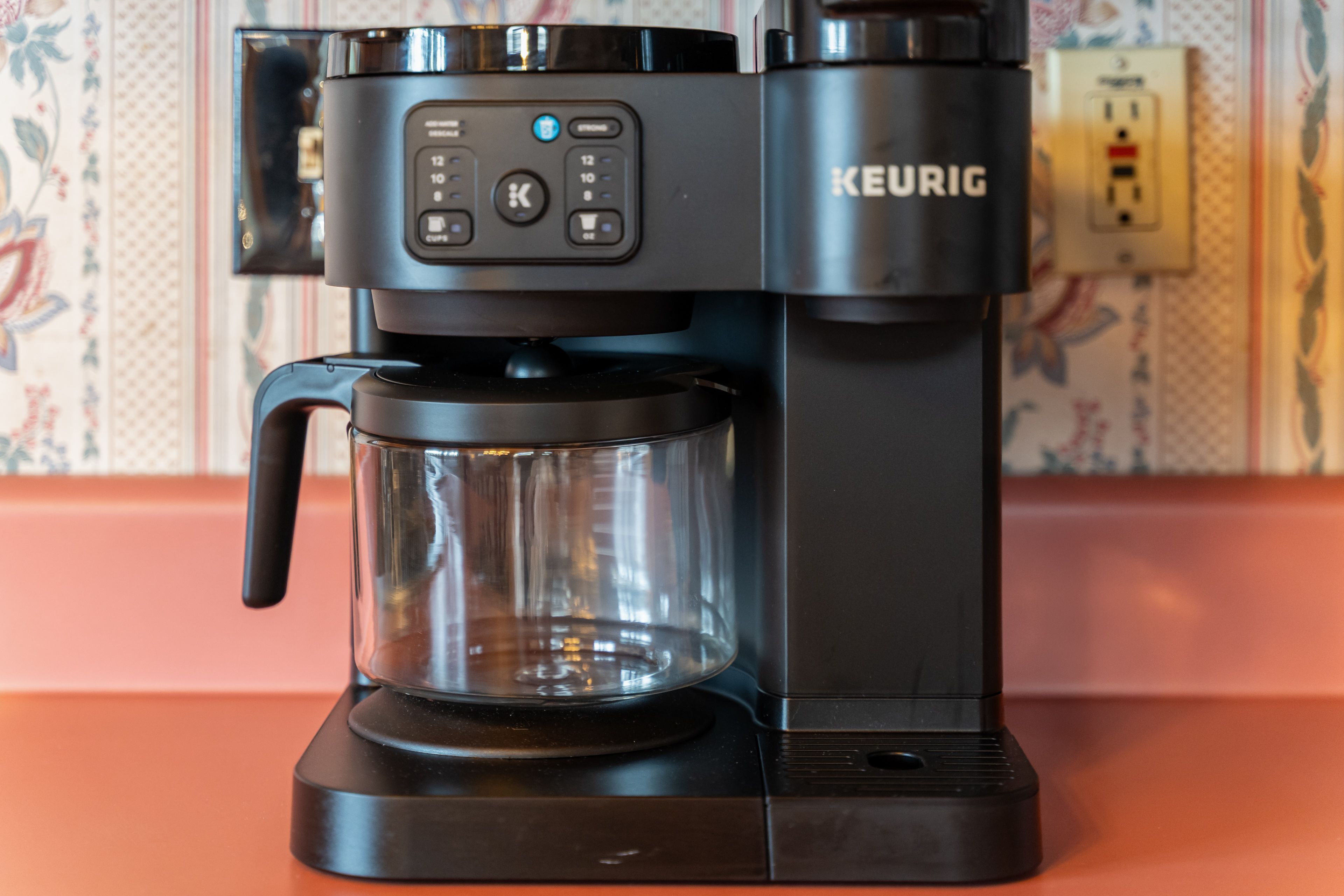 En Keurig kaffemaskine med en glaskande på en bordplade.