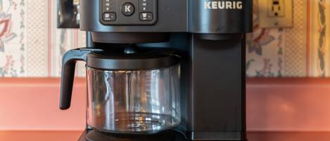 En Keurig kaffemaskine med en glaskande på en bordplade.