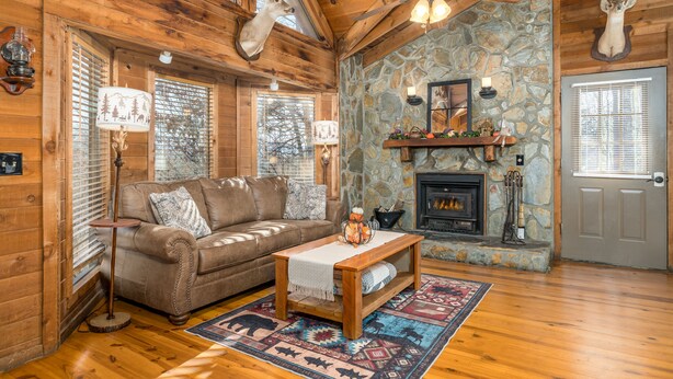 A cozy log cabin interior with a fireplace, a stone wall, and wooden furnishings. - Vista Cabin Getaway – Perfect Views + Dog Friendly (Blue Ridge)