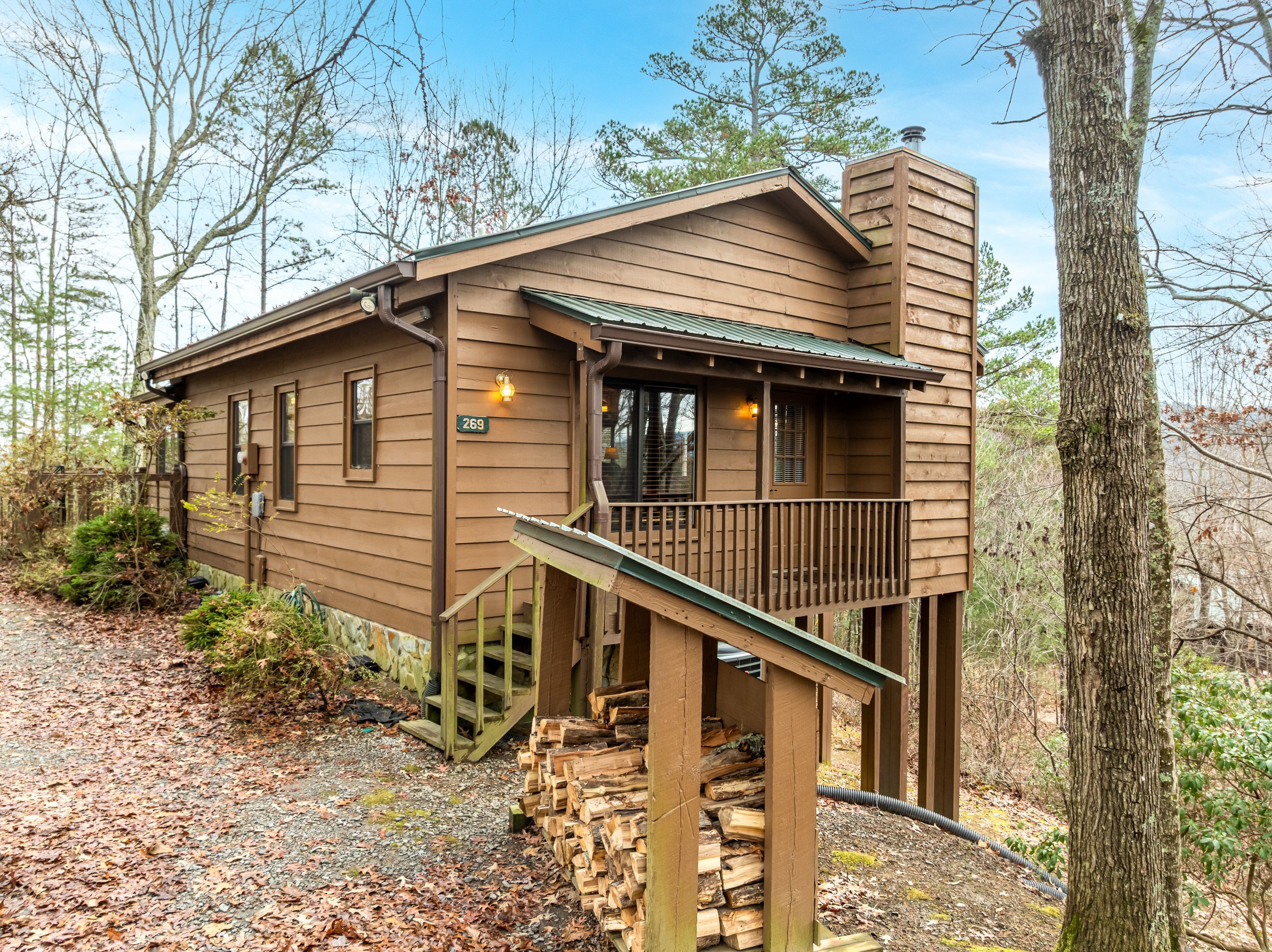A rustic cabin with a porch, a small staircase, and a chimney.