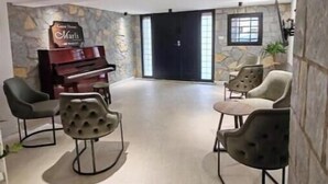 A spacious living area with a piano, comfortable seating, a stone accent wall, and a large window.