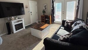 Ein Wohnzimmer mit Flachbildfernseher, Kamin, einer Couch und einem Essbereich.