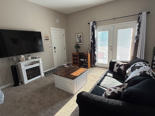 A living room with a flat-screen TV, a fireplace, a sofa, and a dining area.