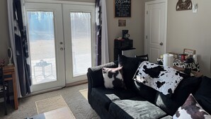En stue med en sofa med sort og hvid købemønster, et kaffehjørne og en oksefigur på væggen.