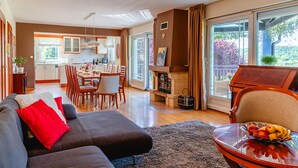 A modern living room with a sofa, a dining area, and a kitchen.