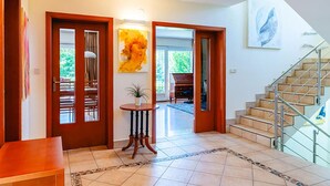 A spacious foyer with a tiled floor, a staircase, and a view of the outdoors.