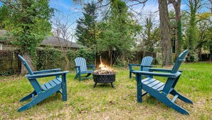 A backyard with two Adirondack chairs and a fire pit. - Southern Gem, Game Rm, Fire Pit, Near Coliseum (Greensboro)