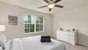 A bedroom with a bed, a ceiling fan, a window, a dresser, and a framed picture on the wall. - Southern Gem, Game Rm, Fire Pit, Near Coliseum (Greensboro)