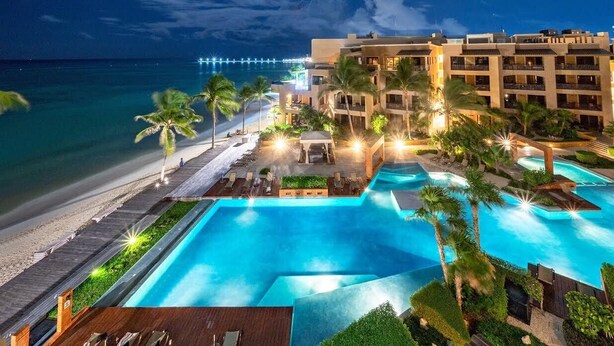 Un resort con una grande piscina, accesso alla spiaggia e vista sull'oceano.