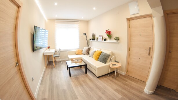 A modern living room with a sofa, coffee table, and a TV mounted on the wall. - Perfecta UbicaciÓn Para Conocer Asturias (Oviedo)