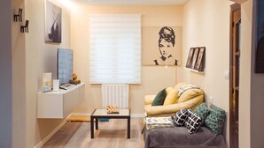 A living room with a sofa, a coffee table, a radiator, and a wall-mounted TV. - Perfecta UbicaciÓn Para Conocer Asturias (Oviedo)