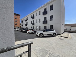 A multi-story building with a row of parked cars in front.