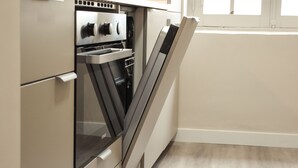 Een moderne keuken met inbouwapparatuur, een raam met zonwering en een lichtgekleurde vloer.
