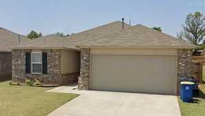 A single-story house with a garage, a front lawn, and a clear sky.