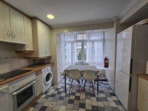 Une cuisine compacte équipée d’un lave-linge, d’une cuisinière et d’une table à manger avec des chaises.