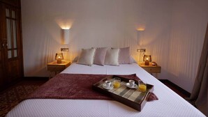 Ein Hotelzimmer mit einem großen Bett, zwei Nachttischlampen, einem Tablett mit Frühstücksangeboten und einem Holzschrank.