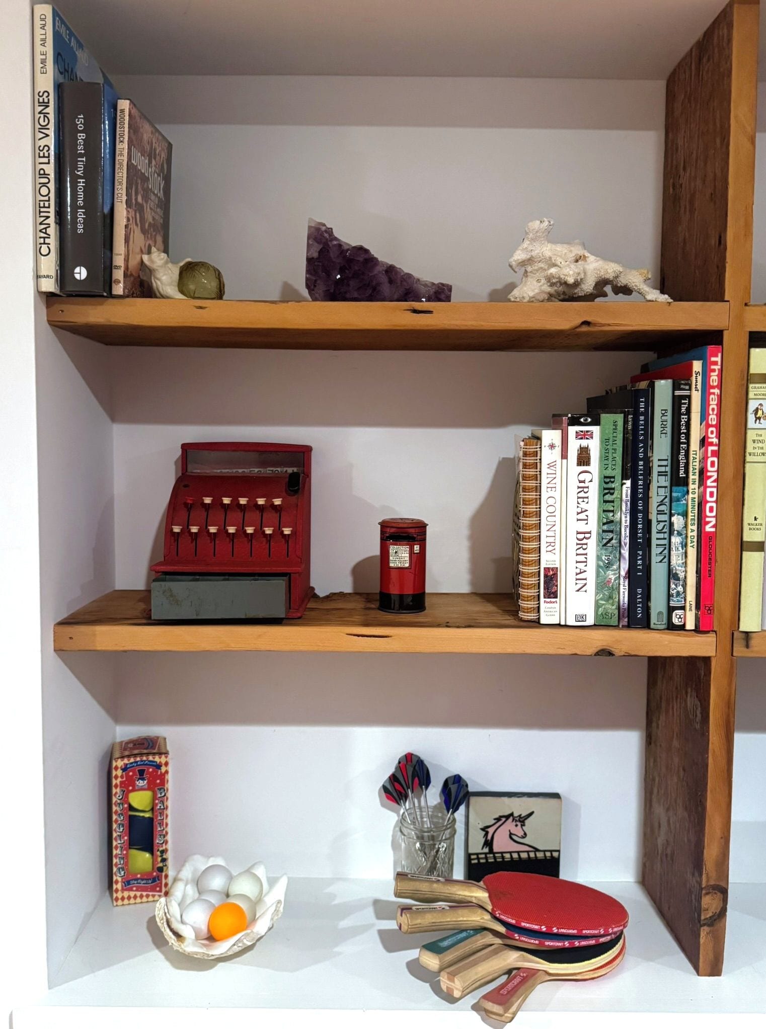 Une bibliothèque remplie de livres, une machine à écrire, une petite figurine et un cristal.
