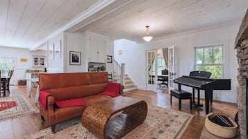 Un salon spacieux avec un canapé en cuir marron, un piano et une cheminée en pierre.