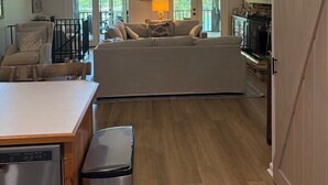 A spacious living area with a high ceiling, a ceiling fan, a fireplace, and a television.