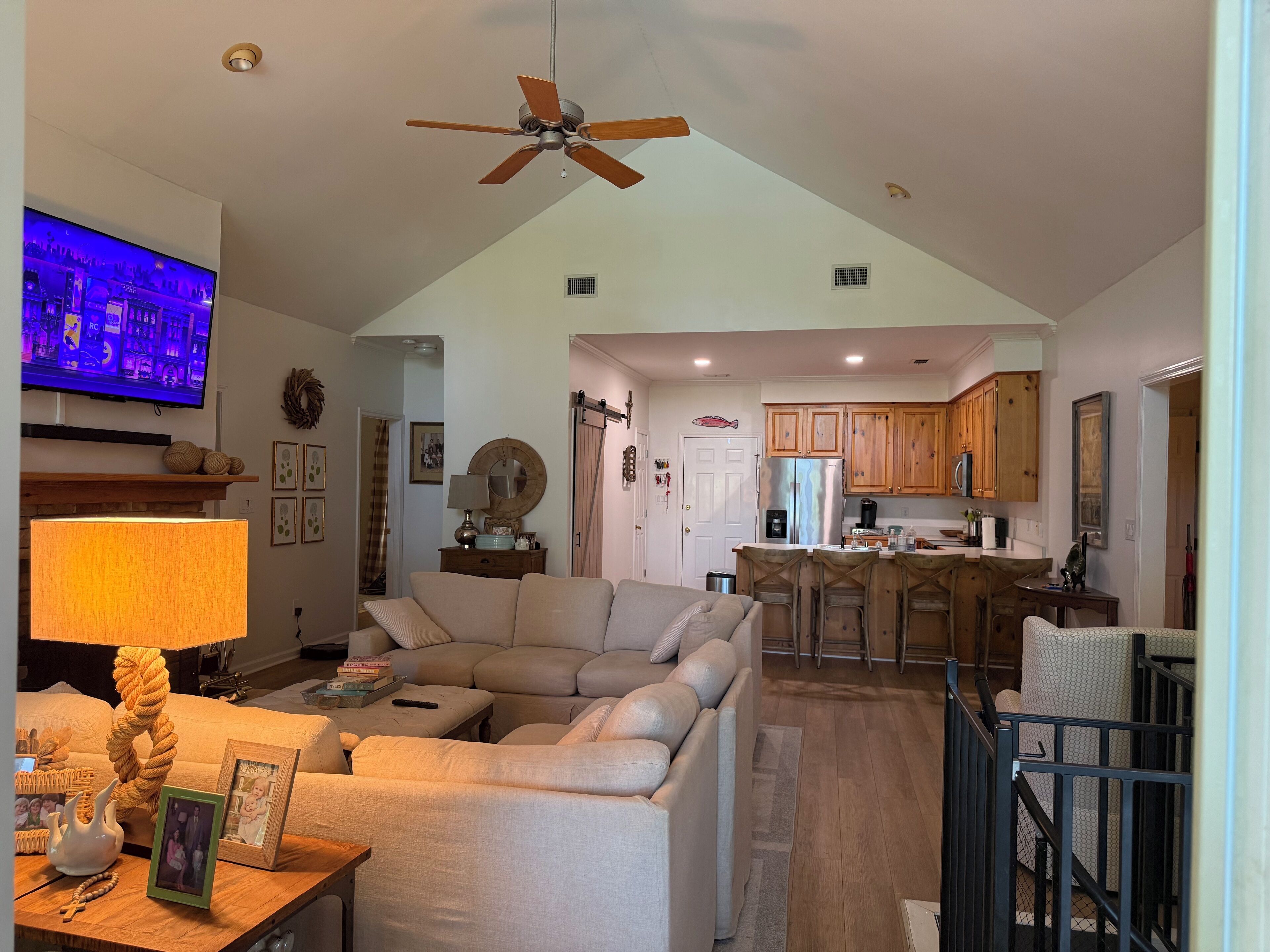 A spacious living room with a large sectional sofa, a ceiling fan, a TV, and a fireplace.