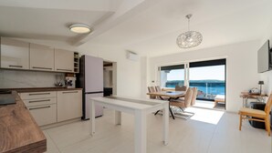 A modern kitchen with white cabinets and a dining area with a table and chairs. - Amazing home in Razanac (Razanac)