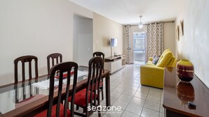 A dining area with a glass table and wooden chairs, a yellow sofa, and a vase on a side table. - 2 Bedroom apt 350m fr the Beach, BC Center Btr0302 (Balneário Camboriú)