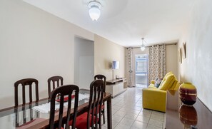 A dining area with a glass table and wooden chairs, a yellow sofa, and a vase on a side table. - 2 Bedroom apt 350m fr the Beach, BC Center Btr0302 (Balneário Camboriú)