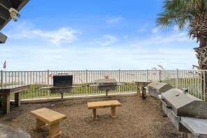An outdoor patio with a grill, benches, and a view of the beach. - Beachfront Condo at Windward Pointe! (Orange Beach)