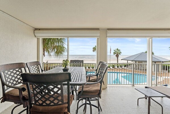 A covered outdoor area with a pool, chairs, and a table.