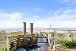 A wooden boardwalk leading to a beach with a view of the ocean and a flag.