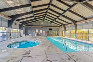 An indoor swimming pool with a covered roof, clear poolside area, and a view of the outside. - Beachfront Condo at Windward Pointe! (Orange Beach)