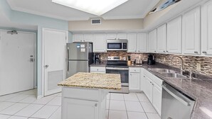 A compact kitchen with white cabinets, a stainless steel refrigerator, a microwave, and a gas stove.