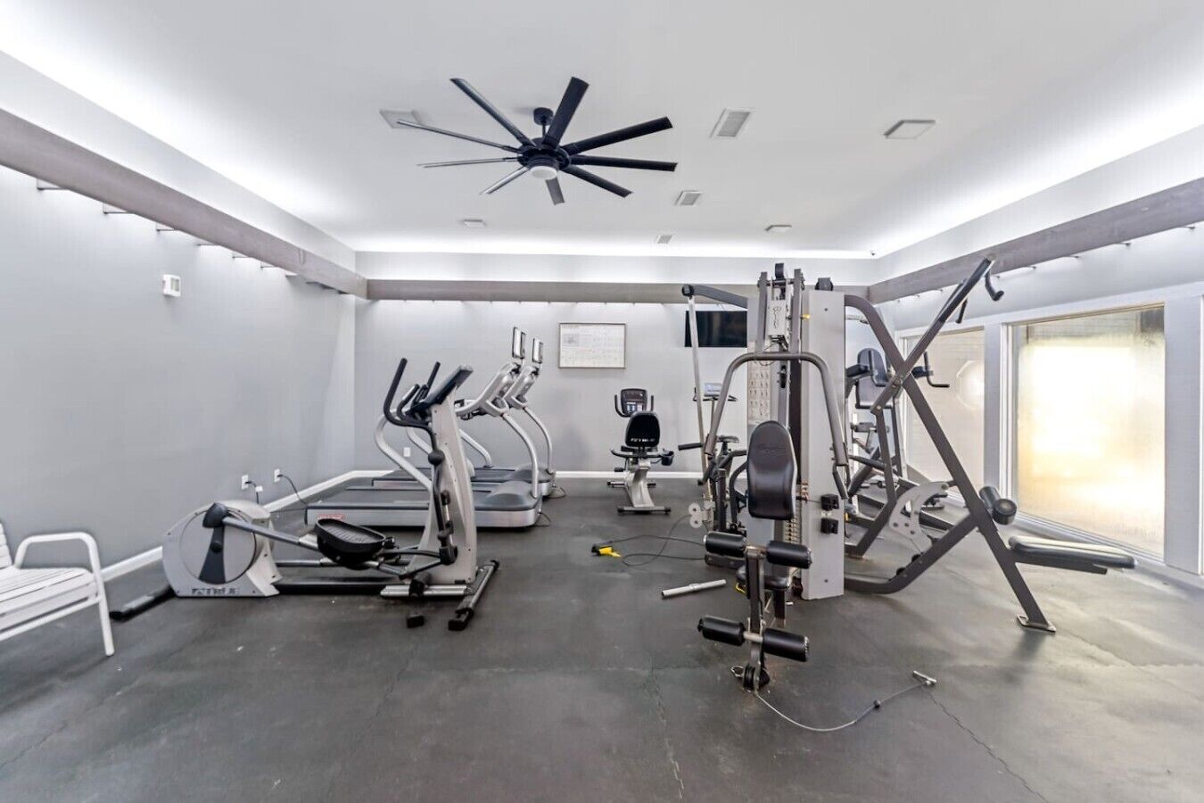 A gym with treadmills, elliptical machines, and weightlifting equipment.