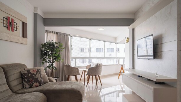 A modern living room with a sofa, a TV, and a dining area with chairs and a table.