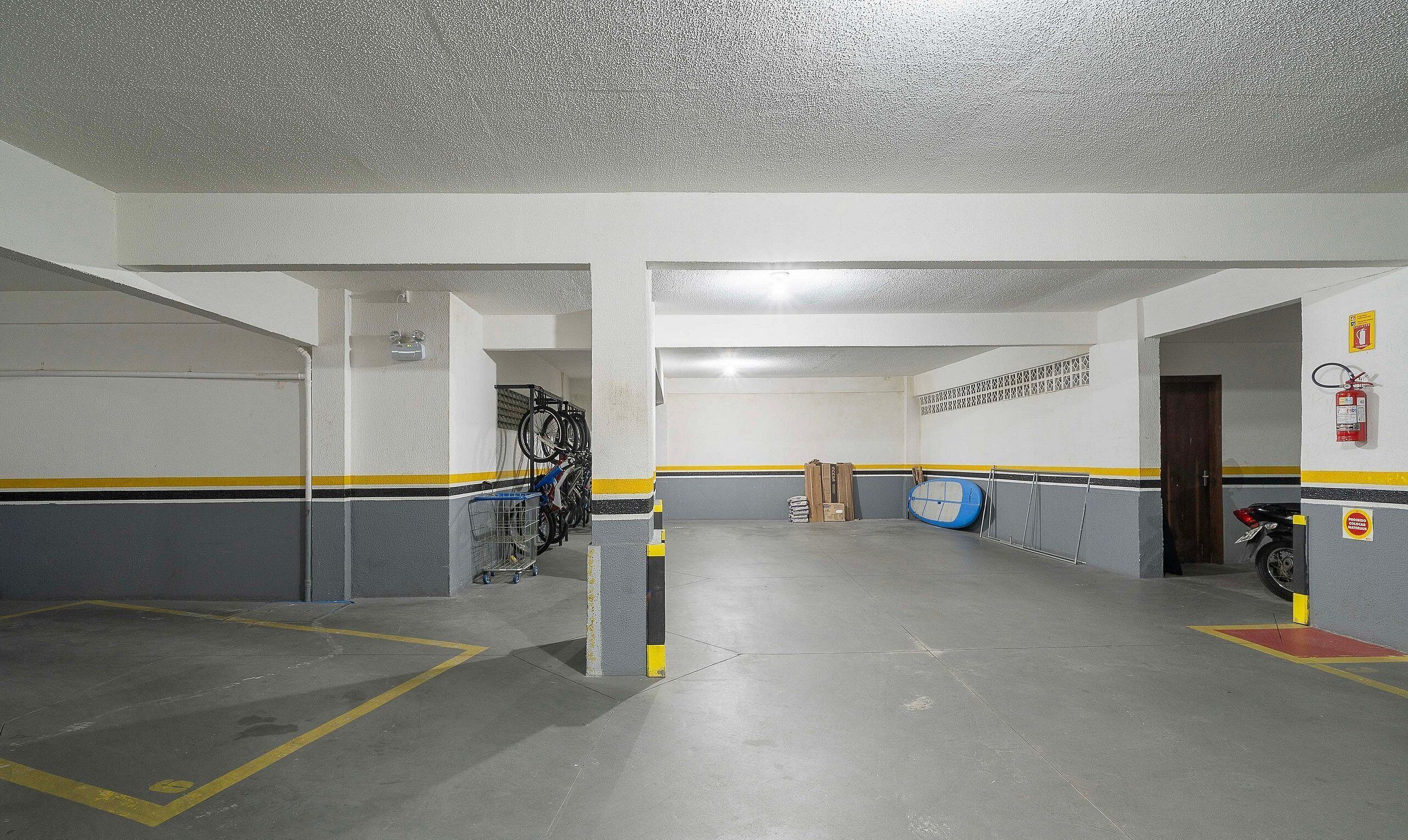 Eine Parkgarage mit Betonböden, Wänden in Gelb-Schwarz-Streifen und einem Feuerlöscher an der rechten Wand.