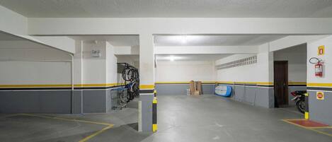 Eine Parkgarage mit Betonböden, Wänden in Gelb-Schwarz-Streifen und einem Feuerlöscher an der rechten Wand.