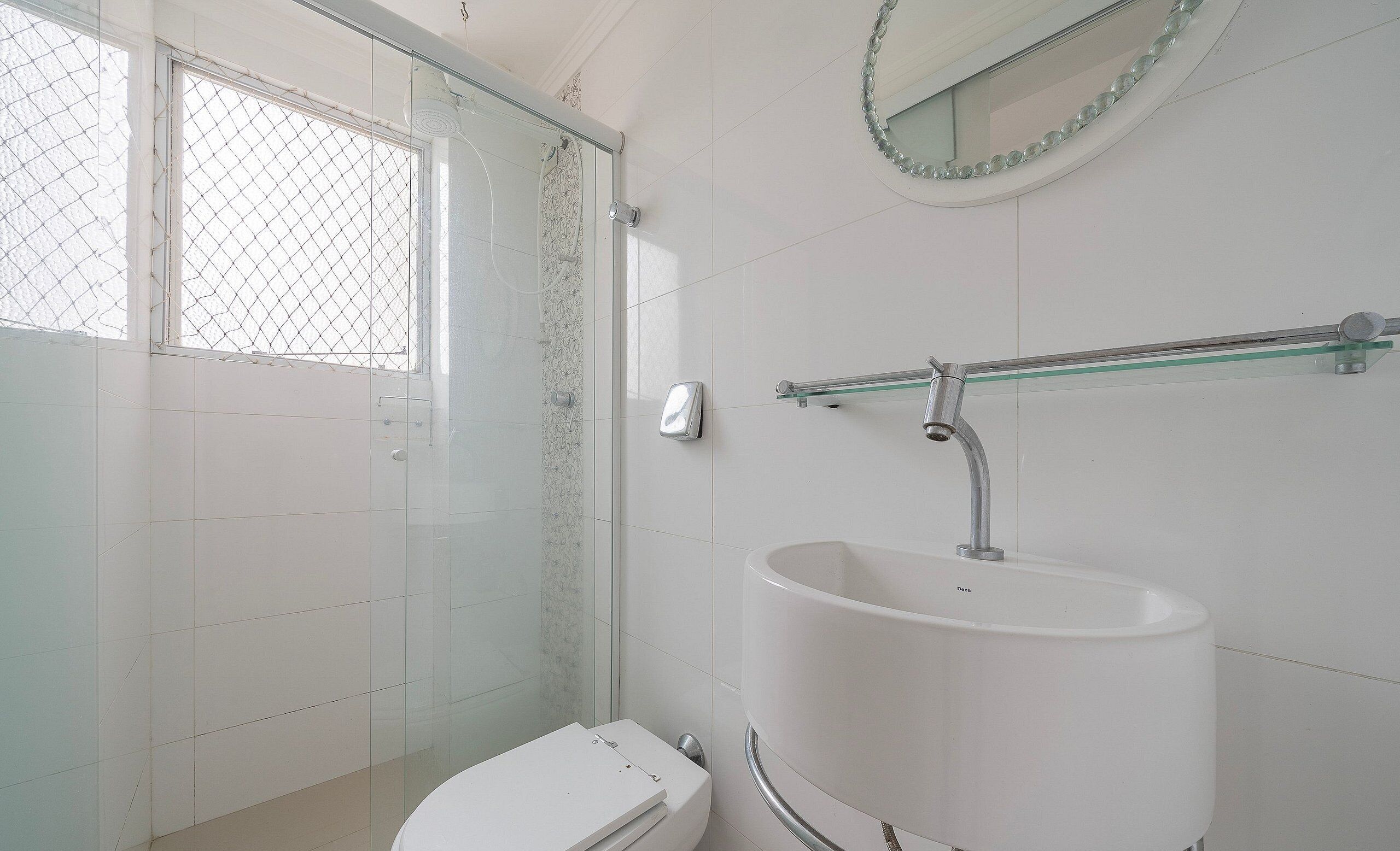 A bathroom with a glass shower enclosure, a white sink, and a toilet.