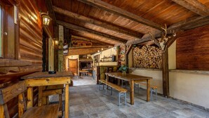 A rustic wooden interior with exposed beams, a fireplace, and a stone-tiled floor.
