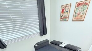 Una cama compacta con cajones para guardar objetos, una mesita de noche y un pequeño escritorio con silla.