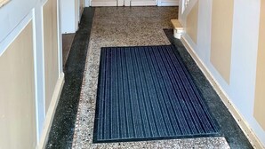Un couloir dont le sol est recouvert d’une moquette, menant à un ensemble de portes doubles ornées de panneaux de vitrail.