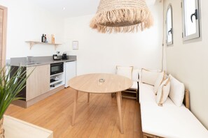 A modern kitchen with wooden cabinets, a round dining table, and a hanging light fixture.