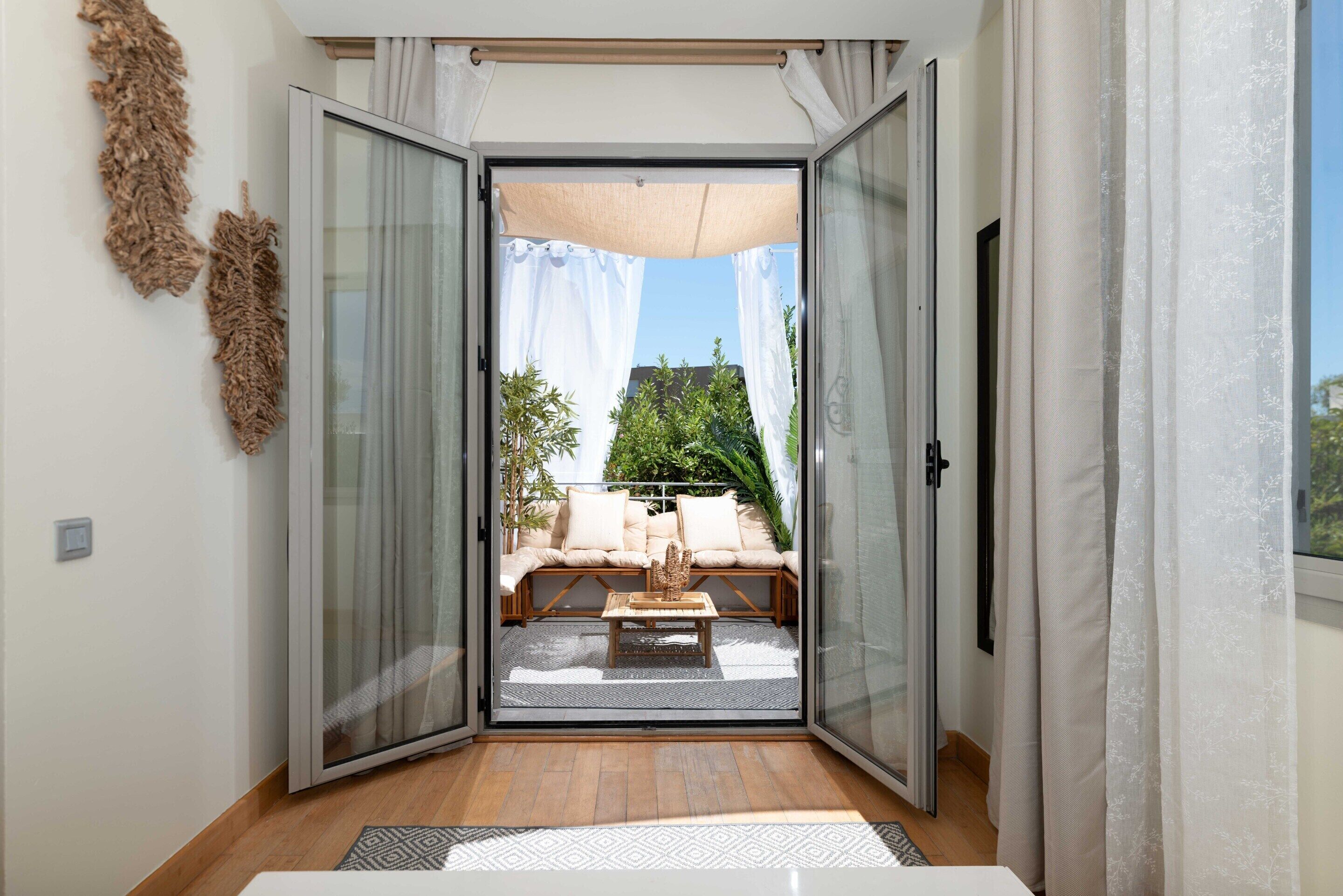 A room with a sliding glass door leading to an outdoor seating area with a sofa and a table.