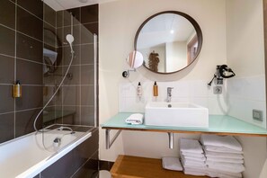 A modern bathroom with a glass shower enclosure, a white sink, and a mirror above it.