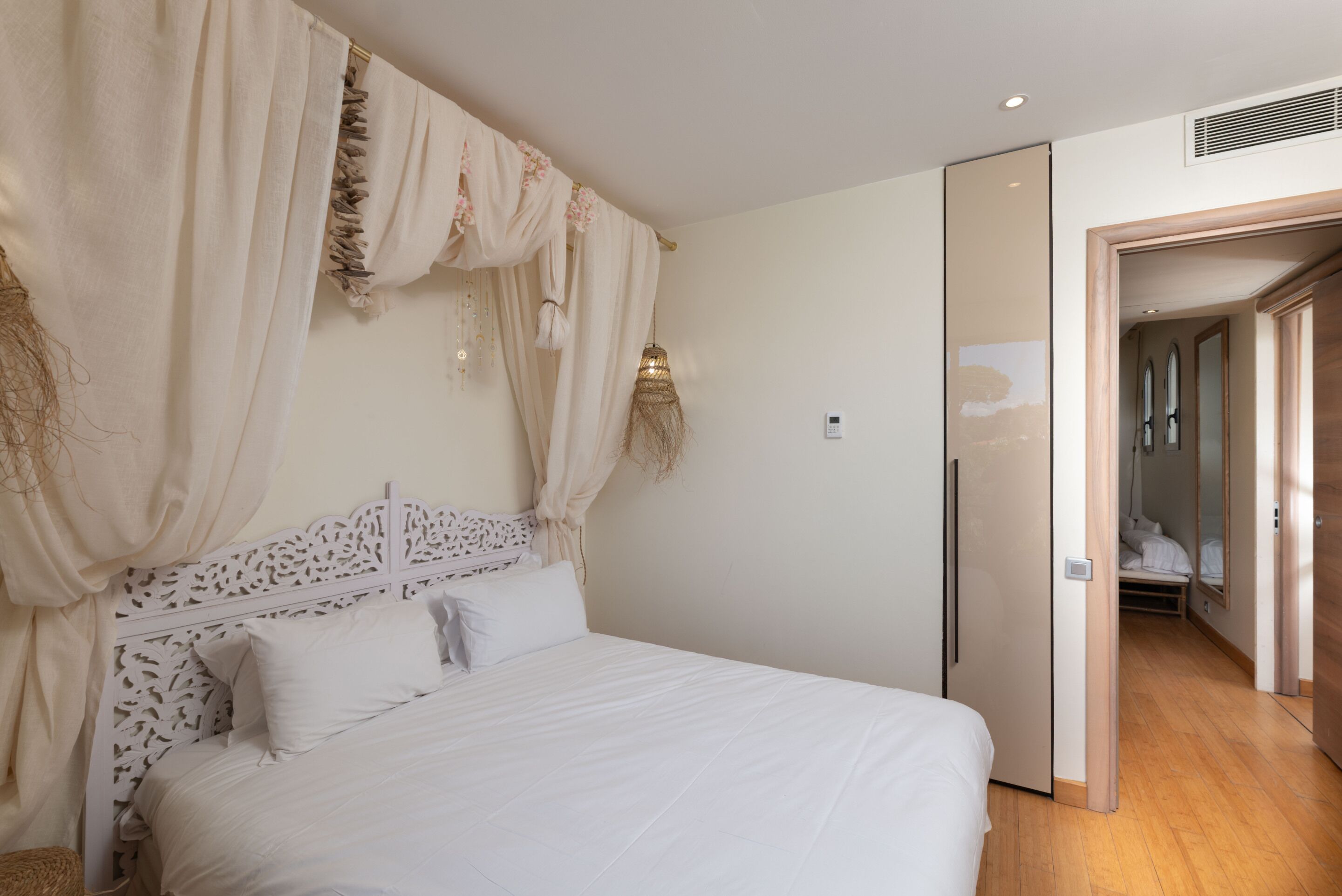 Un dormitorio con cama, cortinas y una puerta que da a otra habitación.
