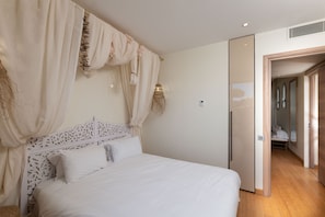 A bedroom with a bed, curtains, and a door leading to another room.