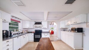 Eine moderne Küche mit weißen Schränken, Holzboden, einem schwarzen Backofen und einer Mikrowelle auf der Arbeitsfläche.