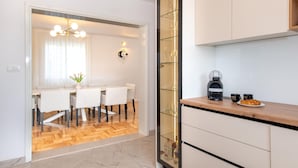 A modern kitchen with a coffee maker, two cups, and a croissant on the counter. - Nice home in Cvrljevo (Cvrljevo)